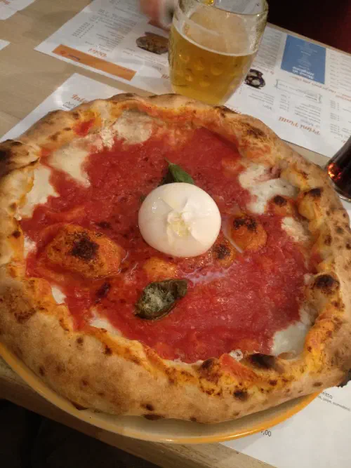 A wood-fired Neapolitan-style pizza with characteristic charred, blistered spotting